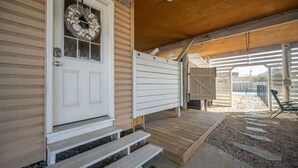 A wooden porch with a white door, steps, and a covered area with a bench. - New! Beach Cottage, Pool, PickleBall, Swim, Surf (Virginia Beach)