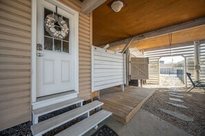 A wooden porch with a white door, steps, and a covered area with a bench. - New! Beach Cottage, Pool, PickleBall, Swim, Surf (Virginia Beach)