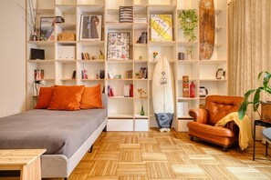Una habitación con una cama, un sillón de cuero, una estantería y una tabla de surf.