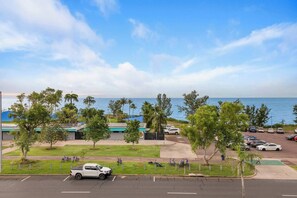 A parking lot with a view of the ocean, a white pickup truck, and several parked cars. - Nightcliff Oceanview Top floor Retreat (Nightcliff)