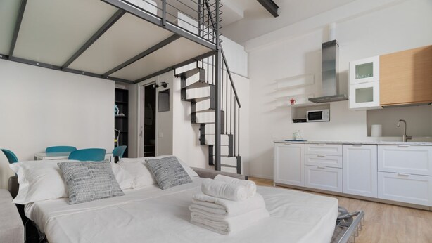 Une chambre d’hôtel moderne comprenant un lit, un escalier, un coin cuisine et un espace salon.