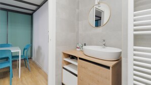 Une salle de bain avec un lavabo blanc, un miroir et un espace douche.