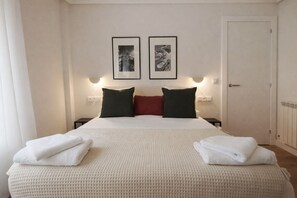 A hotel room with a bed, two framed pictures on the wall, a door, and a nightstand with a lamp. - R2R -Apartment in downtown Oviedo - 660A (Oviedo)