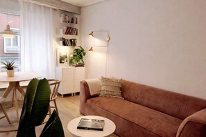 A living room with a sofa, a coffee table with a book, a bookshelf, a plant, and a lamp. - R2R -Apartment in downtown Oviedo - 660A (Oviedo)