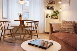 A cozy living room with a round coffee table, a sofa, and a dining area with chairs and a table.