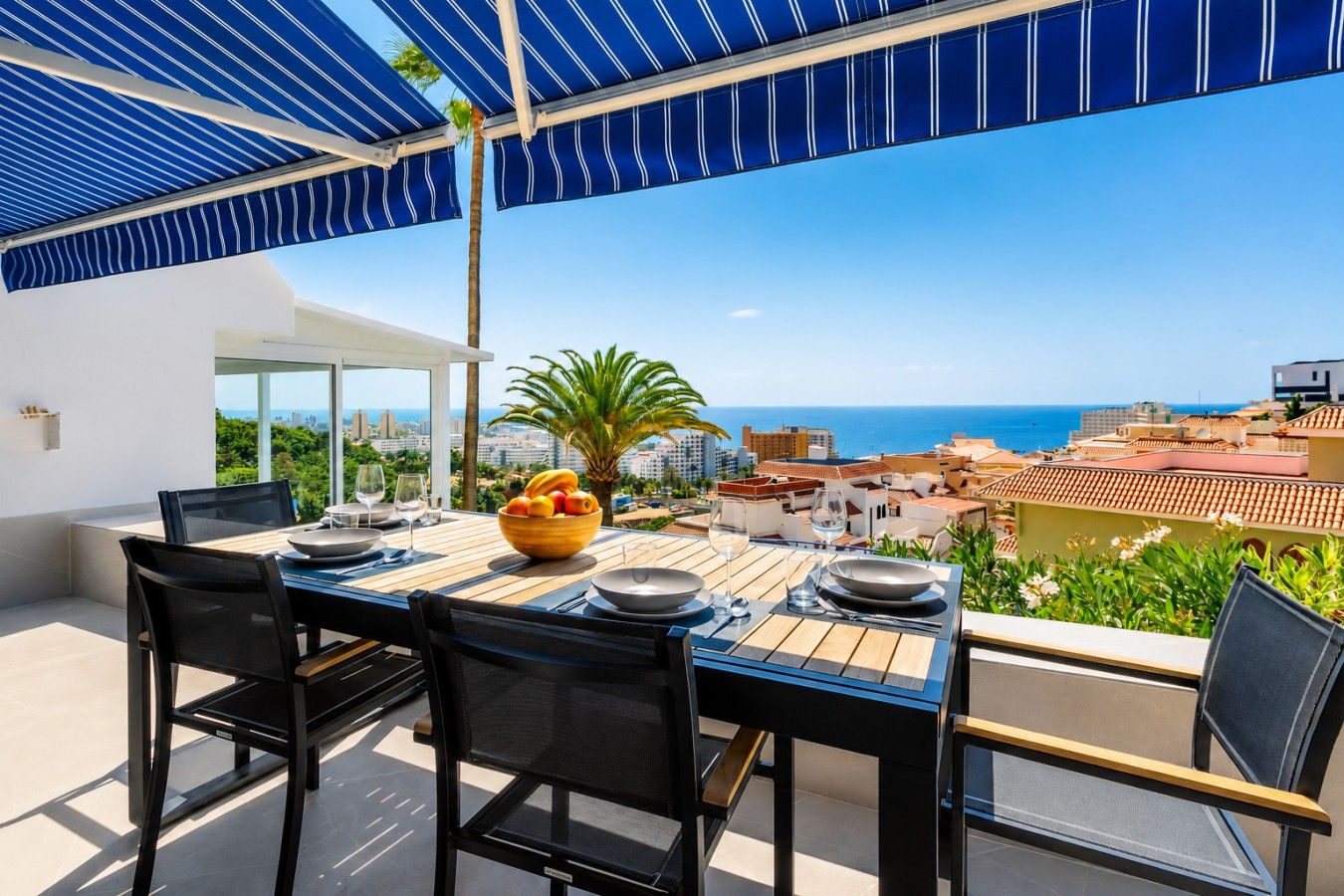 Mesa de comedor al aire libre con vista al mar y al paisaje urbano.