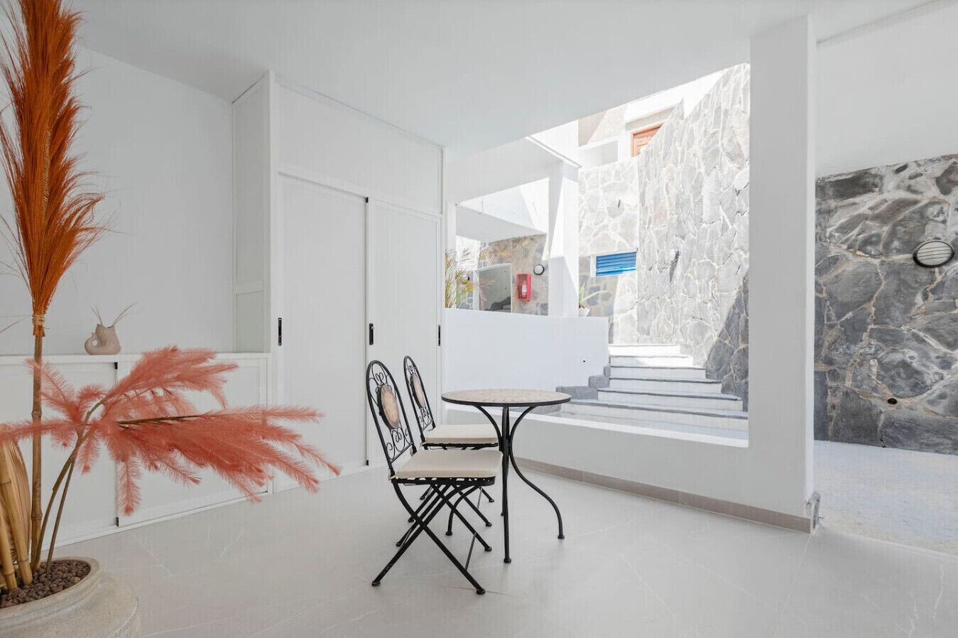 Un intérieur moderne avec un coin repas, des murs en pierre et une vue sur l’extérieur.