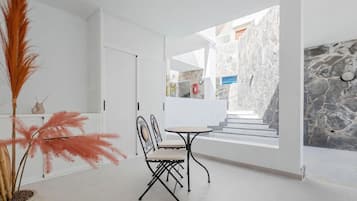 Un intérieur moderne avec un coin repas, des murs en pierre et une vue sur l’extérieur.