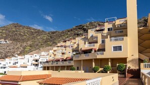 Un quartier résidentiel situé sur une colline, avec des immeubles à plusieurs étages, des balcons et des toits en tuiles de terre cuite.