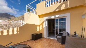 Un balcon avec une chaise, une table et une porte coulissante donnant sur un espace intérieur.