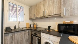 Una cocina compacta con lavadora, microondas y fregadero.