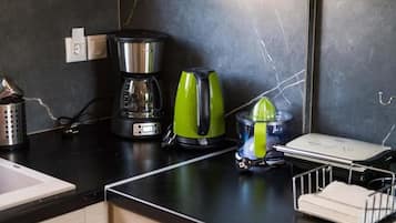 A kitchen counter with a coffee maker, a juicer, and a small appliance.