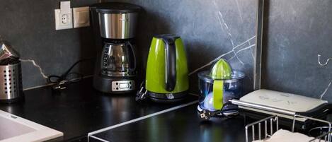 A kitchen counter with a coffee maker, a juicer, and a small appliance.