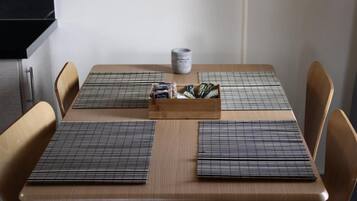 A dining table with placemats, a box of condiments, and a mug.