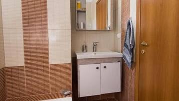 Un baño con bañera, lavamanos, espejo y puerta de madera.