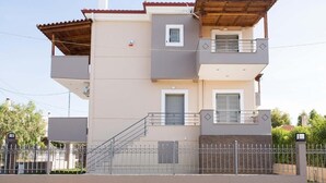 A two-story residential building with a balcony, a staircase, and a gated entrance. - Electra (Aigialeia)