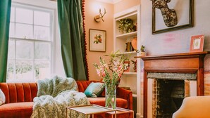 Un salon chaleureux avec un canapé rouge, une cheminée et un vase rempli de fleurs.