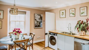 Une cuisine compacte équipée d’un lave-linge, un coin repas avec une table et des chaises, et une fenêtre donnant sur un paysage agréable.