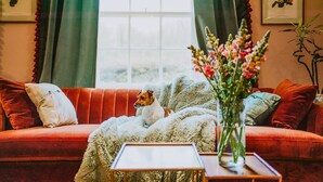 Un salon chaleureux avec un canapé rouge, une couverture blanche et moelleuse, une petite table et un vase rempli de fleurs.