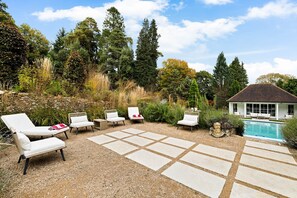 A poolside area with lounge chairs and a stone pathway leading to a pool.