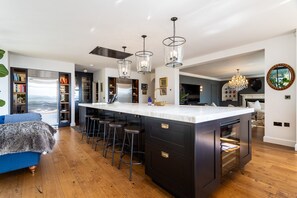 A modern kitchen with a central island, bar stools, and pendant lighting.
