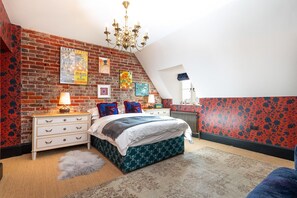 Un dormitorio con pared de ladrillo, una araña, una cama con ropa de cama estampada y un radiador.