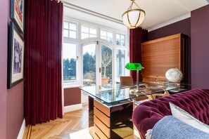 A room with a glass desk, a globe, and a green desk lamp.