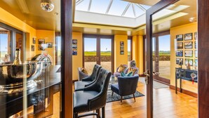 A room with a glass partition, a dining table, chairs, a disco ball, and a view of the outdoors.