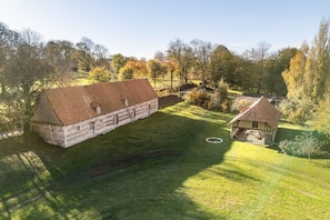 A large brick building with a sloped roof, surrounded by a well-maintained lawn and trees.