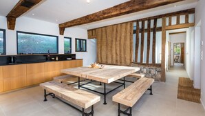 A modern kitchen with wooden cabinetry, a large island, and a dining area with benches.