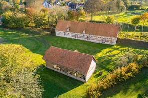 A large stone building with a tiled roof, surrounded by a well-maintained lawn and trees.
