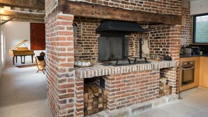 A brick-built kitchen with a built-in oven, a piano, and a rustic ambiance.