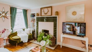 A living room with a green sofa, a fireplace, a television, and a star decoration on the wall.