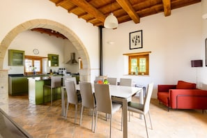 Una cocina amplia con isla, un área de comedor con sillas, un sofá rojo y un arco de piedra.
