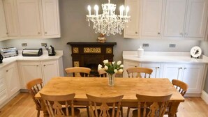 A dining room with a wooden table and chairs, a chandelier, and white cabinets.