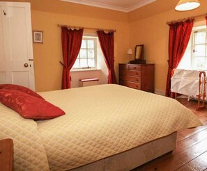 A bedroom with a bed, a dresser, a chair, and a window with curtains.