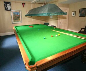 A pool table with balls, a hanging cloth, and a U.S. Marines poster.