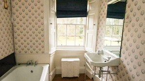 A bathroom with a bathtub, a sink, and a window.