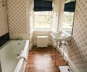 A bathroom with a bathtub, a sink, and a window.