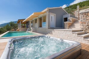 Ein Pool mit Whirlpool, eine Steintreppe und eine überdachte Sitzgelegenheit im Freien.