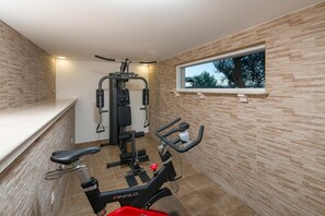 Ein Fitnessstudio mit einem Fahrradergometer, Krafttrainingsmaschine und einem Fenster mit Blick.
