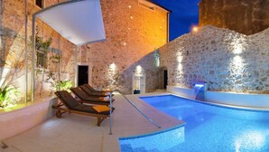 An indoor swimming pool with lounge chairs, a water feature, and stone walls. - Villa Antea - Five Bedroom Villa, Sleeps 12 (Bol)