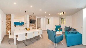 A modern living space with a dining area, a kitchen with a stone accent wall, and a blue sofa. - Villa Antea - Five Bedroom Villa, Sleeps 12 (Bol)