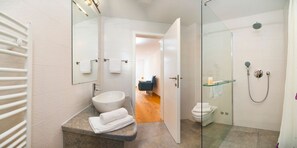 Une salle de bain moderne avec une douche à parois de verre, un lavabo blanc et des toilettes apparentes.