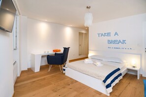 Une chambre d’hôtel moderne équipée d’un lit, d’un bureau, d’une chaise et d’un mur orné d’un message motivant.