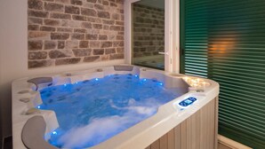 A hot tub with blue LED lights, a stone wall, and a sliding door. - Villa Antea - Five Bedroom Villa, Sleeps 12 (Bol)
