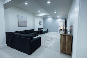 Ein modernes Wohnzimmer mit einem Ecksofa, einem kleinen Tisch und einem Holzschrank.