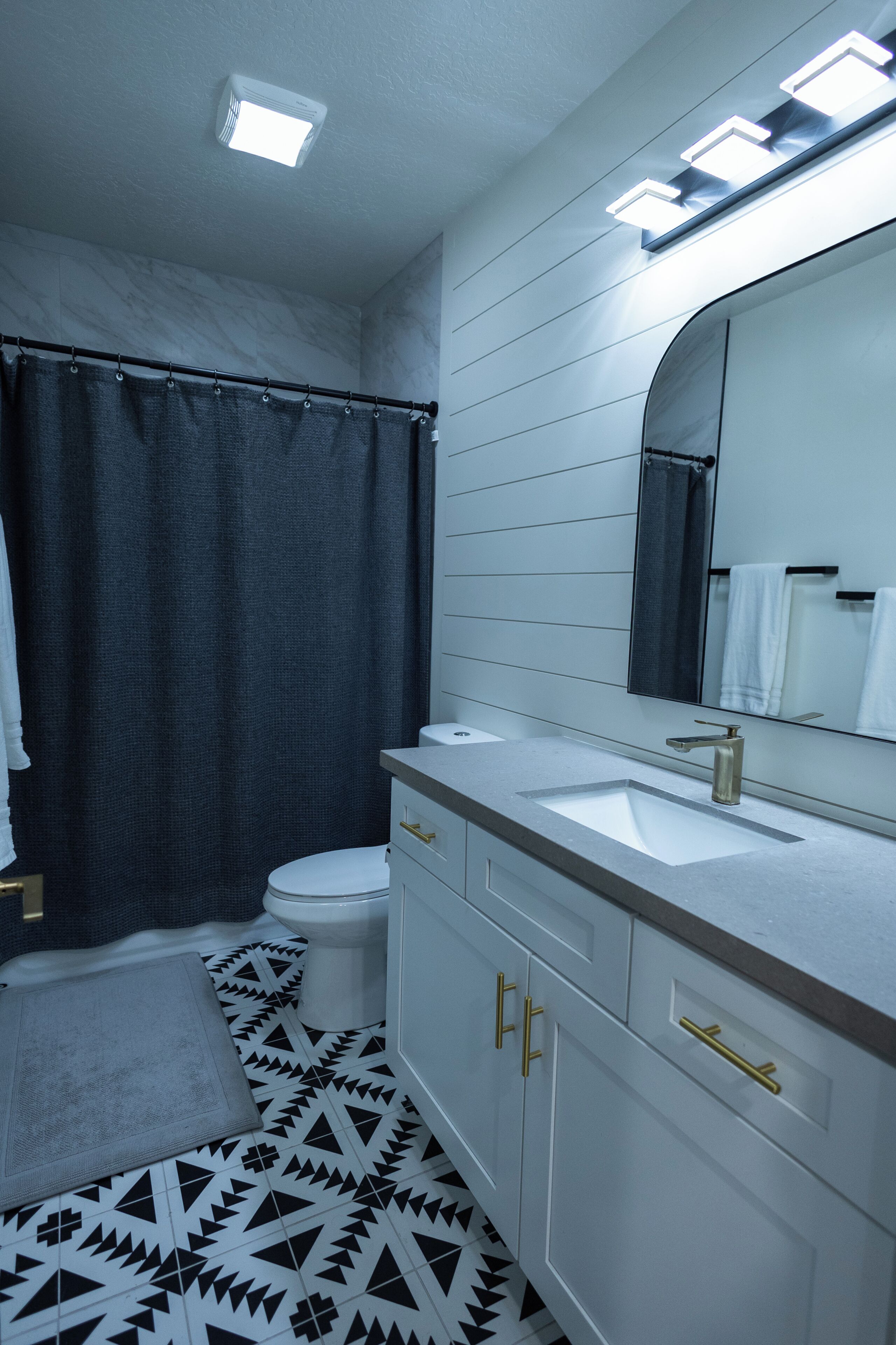 A bathroom with a white sink, a mirror, a toilet, and a shower curtain.
