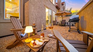 An outdoor patio with a wooden table set for dining, a grill, and a chair with a lamp. - Carmel Valley Gem - Pool, Tennis & Garage (San Diego)