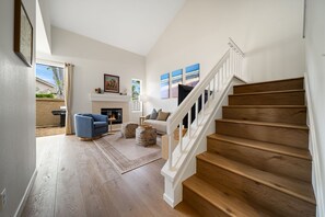 A spacious living room with a fireplace, a staircase, and a view of the outdoors. - Carmel Valley Gem - Pool, Tennis & Garage (San Diego)